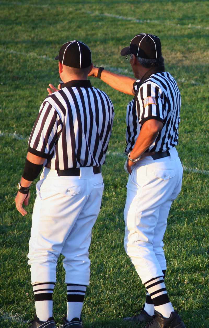 Two football officials making a call on the field